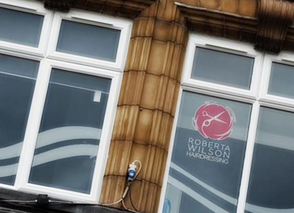 Printed window graphics with the Roberta Wilson Hairdressing logo on a first floor salon window