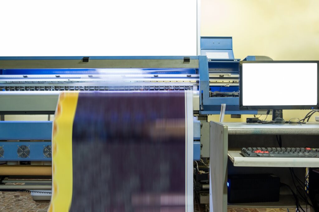 Large inkjet printer working on vinyl banner with computer