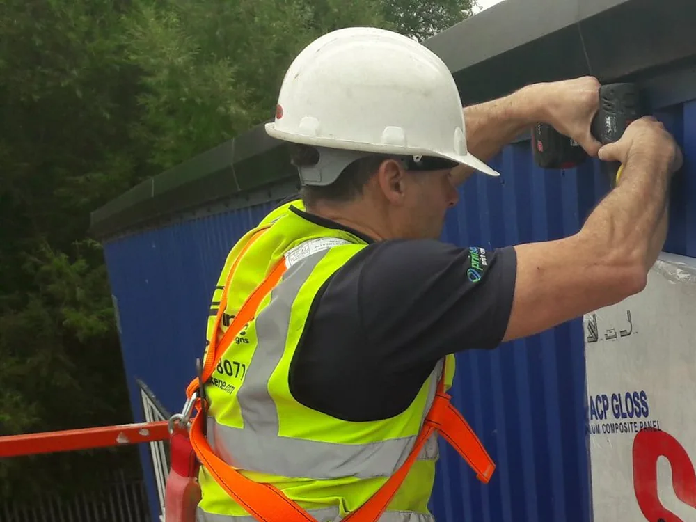 A Printscene fitter installing a large exterior business sign from a cherry picker