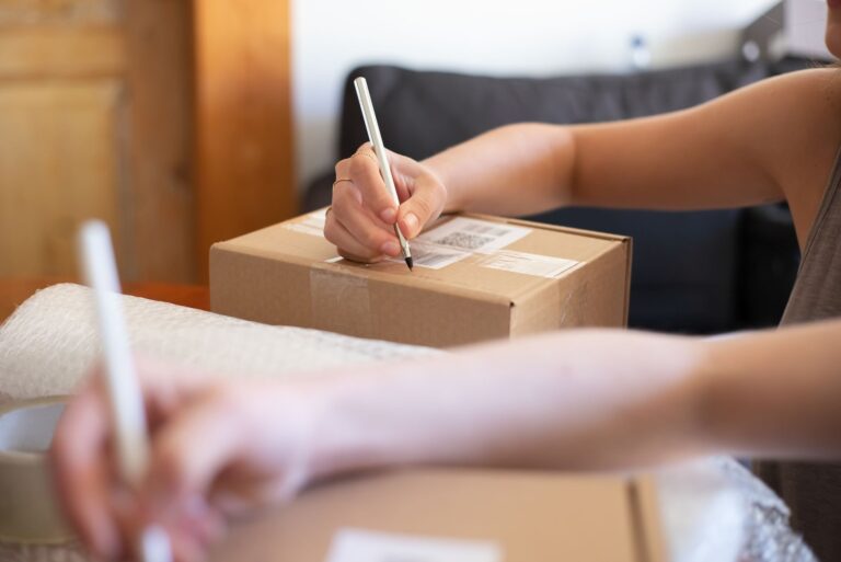 Close-up of hands labelling a box in a small business workshop