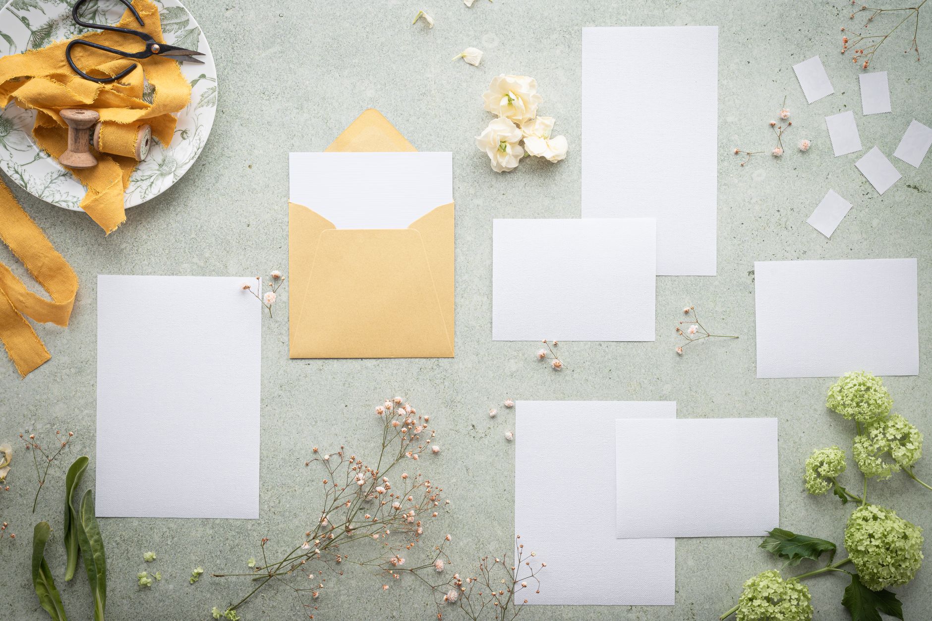 Flat lay of blank wedding stationery with an envelope, ribbon and dried flowers