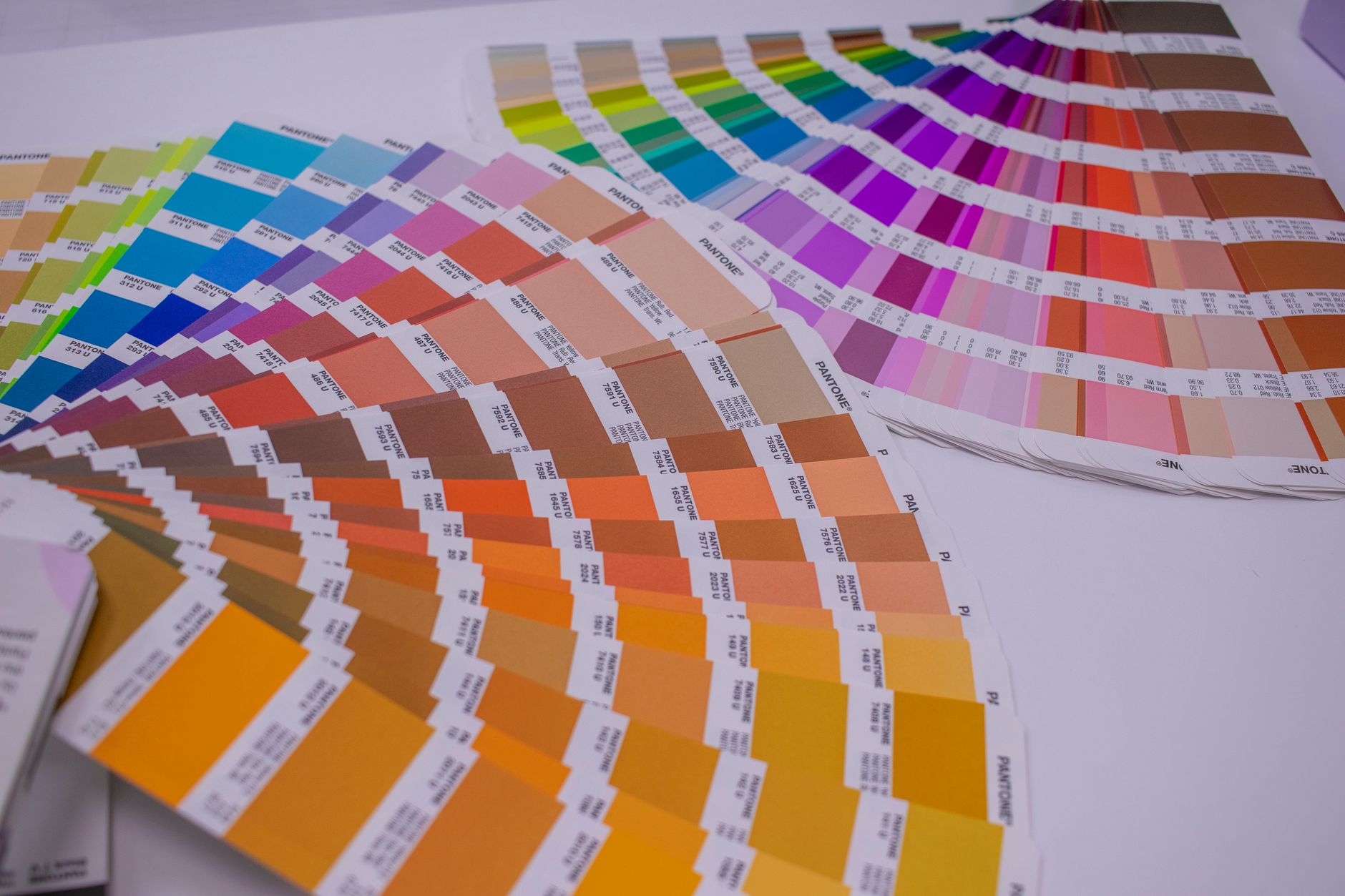 RGB vs CMYK printing: fanned Pantone colour swatch guides on a print workshop desk