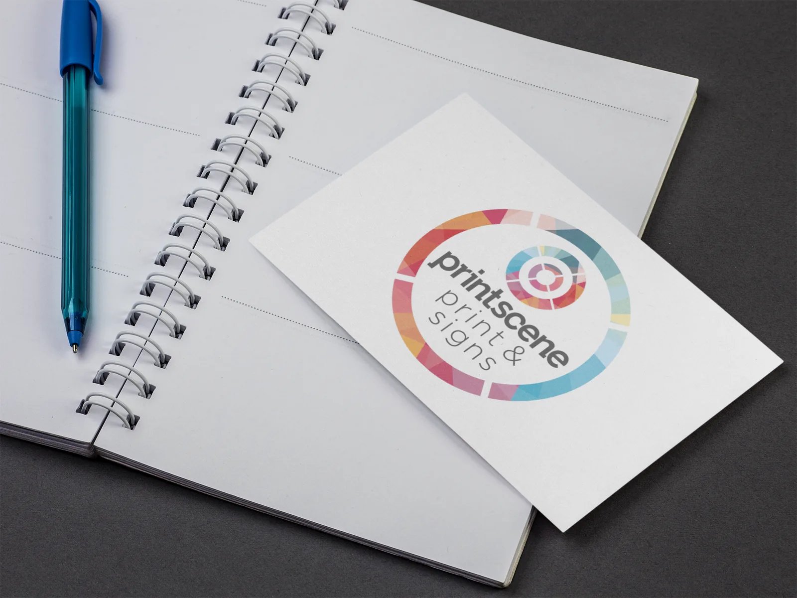 Printscene-branded postcard resting on an open spiral notebook